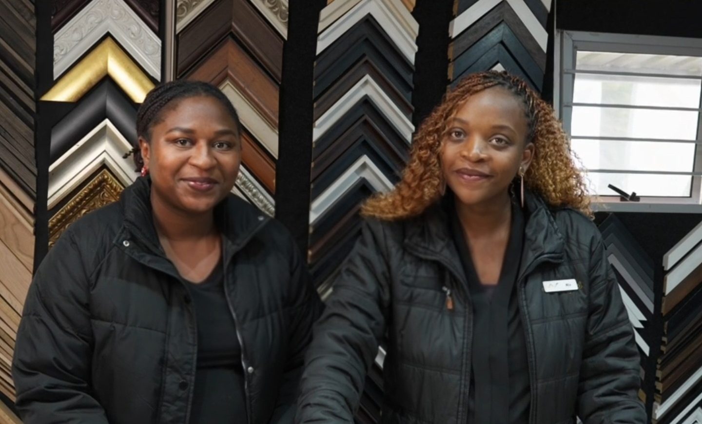 Two Wechi team members in front of the moulding wall